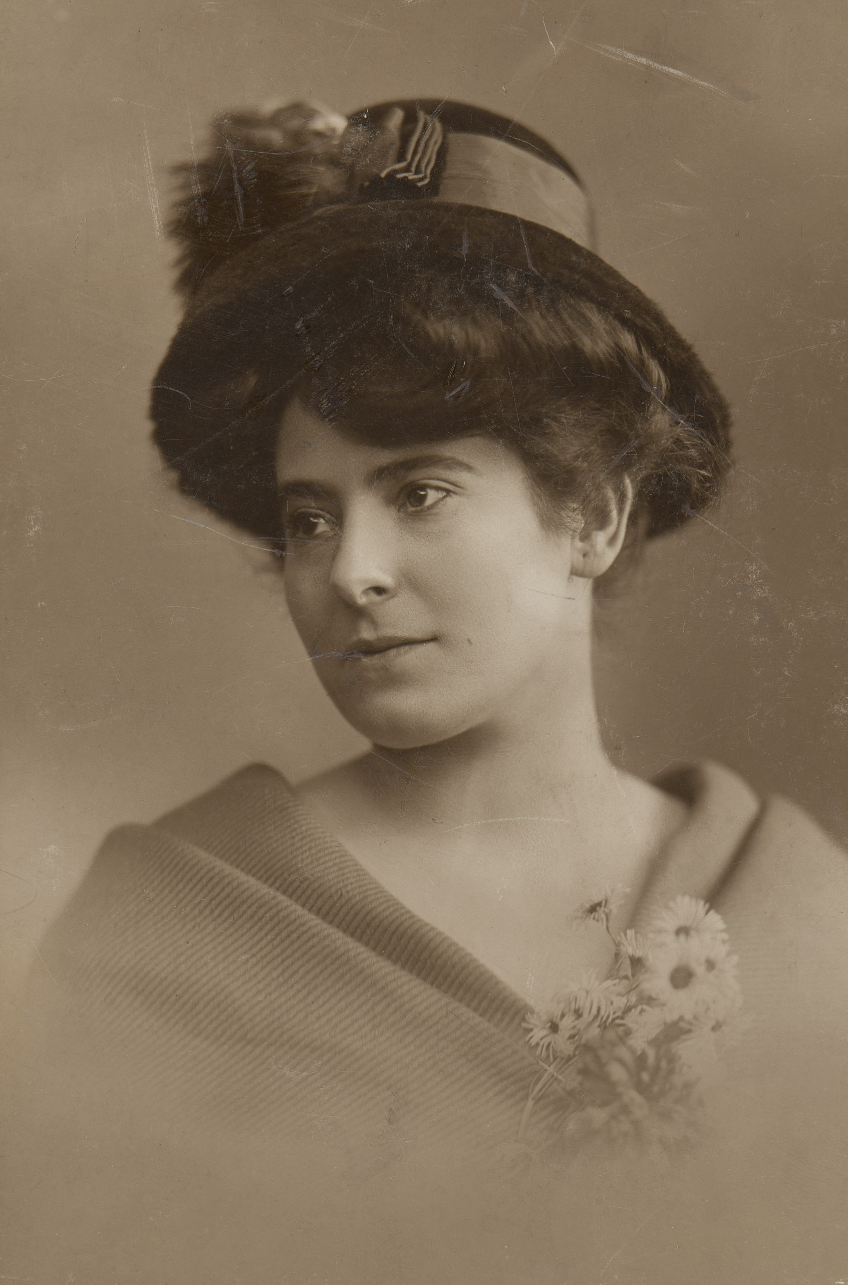 KI generiert: Das Bild zeigt eine Frau in einem historischen Porträt, gekleidet mit einem Hut und einem Umhang oder Schal, während sie zur Seite schaut. Sie hält einen kleinen Blumenstrauß in der Hand.